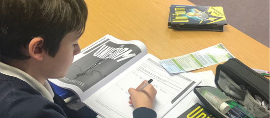 Student sitting at desk writing in a workbook