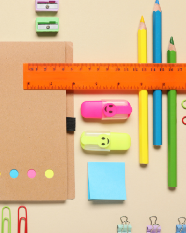 An illustration of stationery laid in a pattern including a notepad and pens