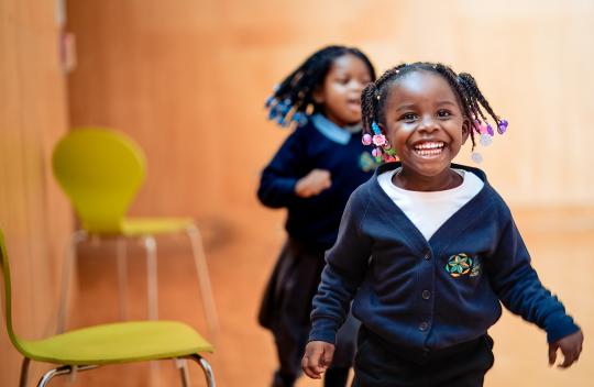 Two girls run towards the camera dressed in school uniform